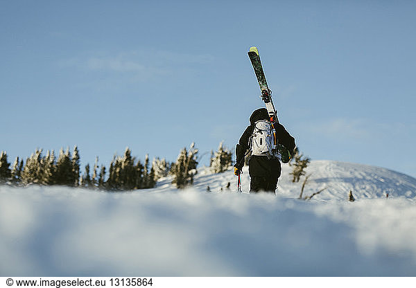 Rückansicht eines Mannes mit Himmel  der auf einem schneebedeckten Berg gegen den Himmel läuft