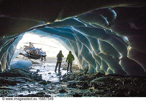 Rückansicht eines Paares  das während einer Luxus-Hubschraubertour eine Eishöhle entdeckt