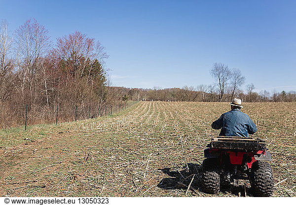 Rückansicht eines Quadfahrers auf einem Bauernhof vor blauem Himmel