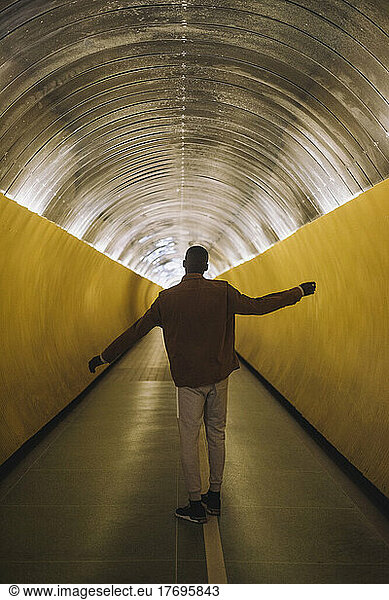 Rückansicht in voller Länge eines jungen Mannes  der in einem U-Bahn-Tunnel tanzt