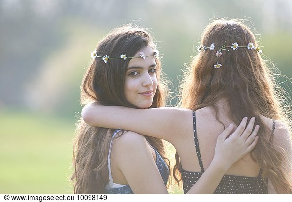 Rückansicht Porträt von zwei Teenager-Mädchen mit Gänseblümchen-Kopfbedeckung im Park