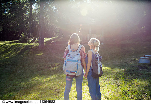 Rückansicht von zwei Freundinnen auf der Waldwiese  Sattelbergalm  Tirol  Österreich