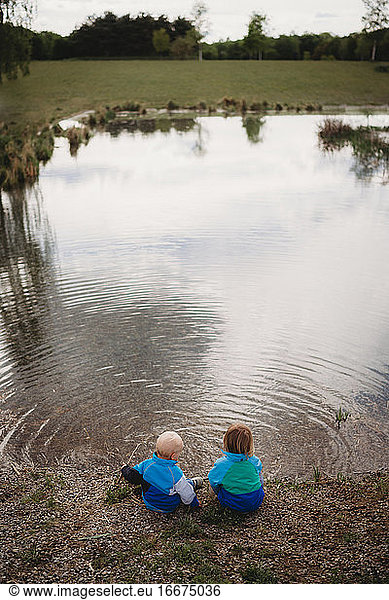 Rückenansicht von Brüdern vor einem See in einem Park an einem bedeckten Tag