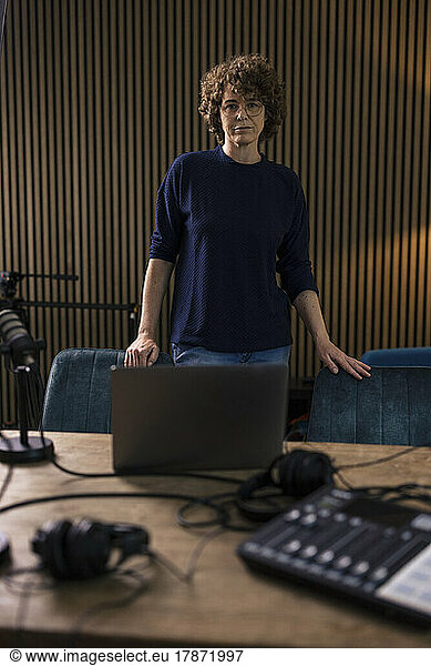 Radio DJ standing by desk in recording studio