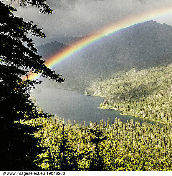 Rainbow and cloudy skies over a alpine lake.