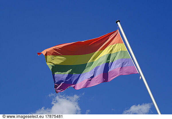Rainbow flag fluttering against sky