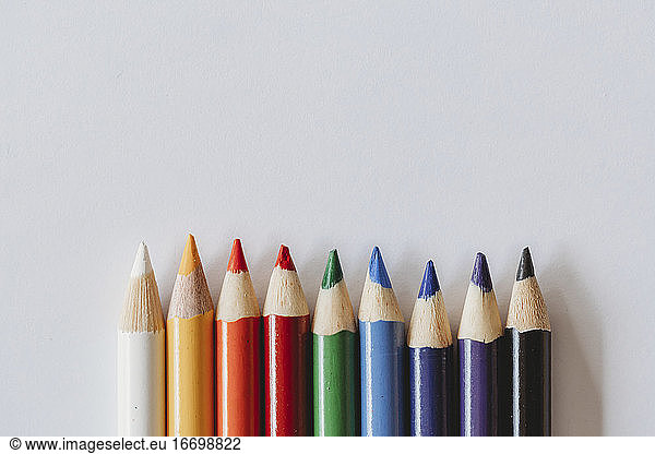 Rainbow of coloring pencils on plain white background