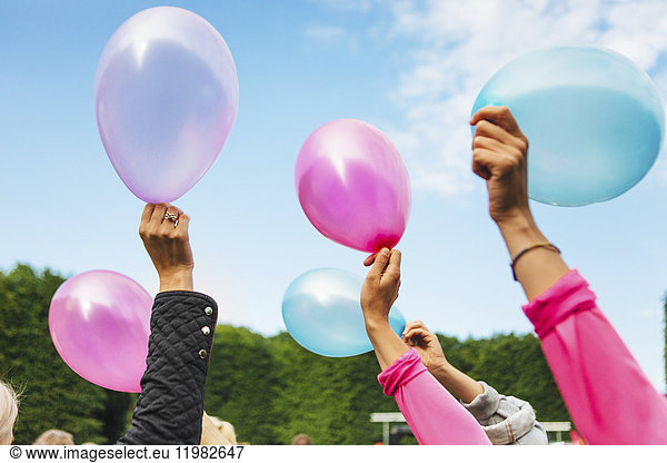 Raised hands holding balloons