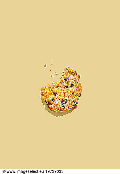 Raisin cookie with missing bite against yellow background