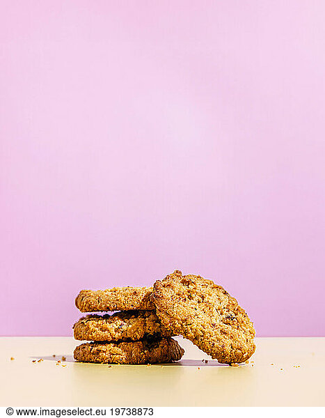 Raisin cookies stacked against pink colored background