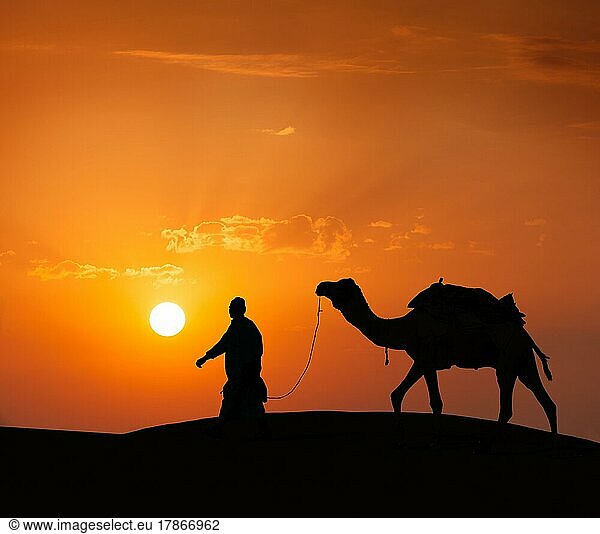 Rajasthan Reise Hintergrund  indische Kameleer (Kameltreiber) mit Kamelsilhouette in den Dünen der Wüste Thar bei Sonnenuntergang. Jaisalmer  Rajasthan  Indien  Asien