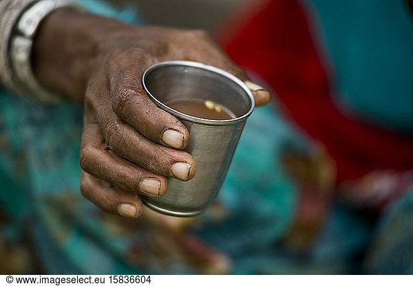 Rajasthani woman holding a metal cup of masala chai