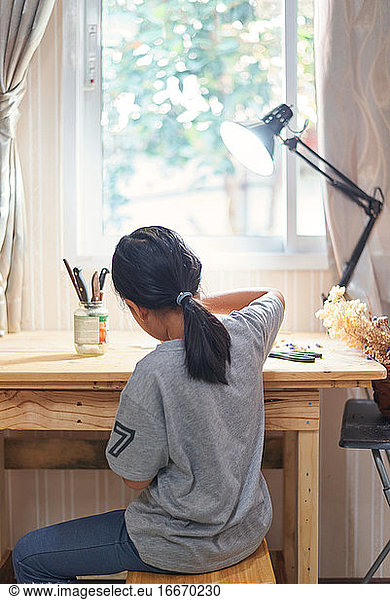 Rare view of a girl working on the wooden table