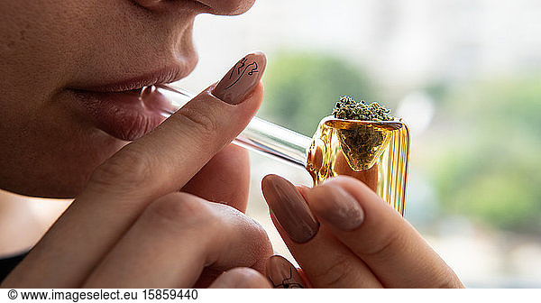 Rauchen von Cannabis durch glasgelbe Tube Nahaufnahme. Kultur des Rauchens