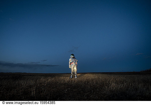 Raumfahrerin steht abends auf der Wiese