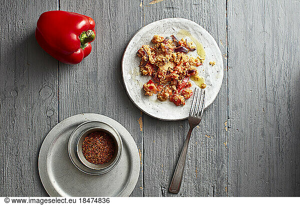 Raw bell pepper  chili powder and plate of ready-to-eat couscous