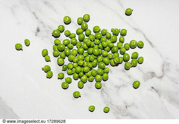Raw green peas lying on marble surface