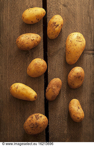 Raw potatoes on wooden table  close up