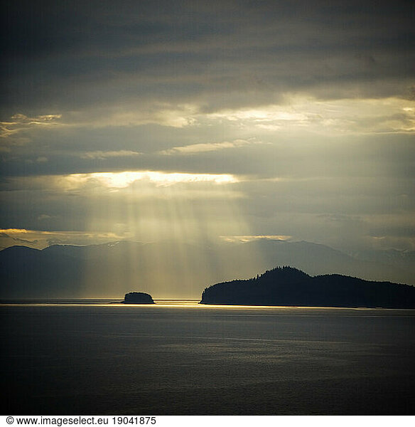 Rays of sun over water and islands along the inland passage in Alaska.