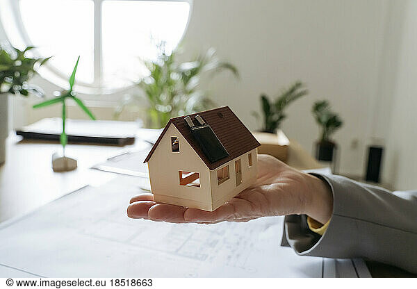 Real estate agent holding model house with solar panel