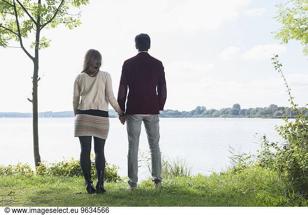 Rear view couple standing lake shore romantic