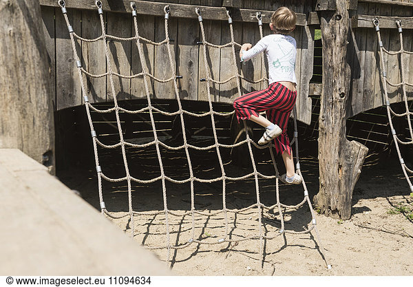 Rear view of a boy climbing on rope in adventure playground  Bavaria  Germany