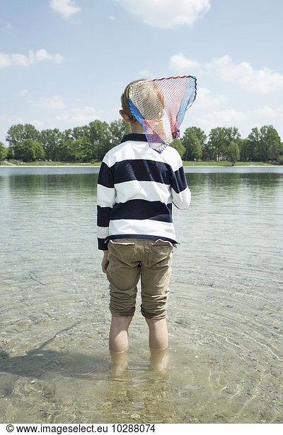 Rear view of a boy holding a brailer in the lake  Bavaria  Germany