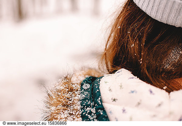 Rear view of a girl with snow on her fur hood and hair