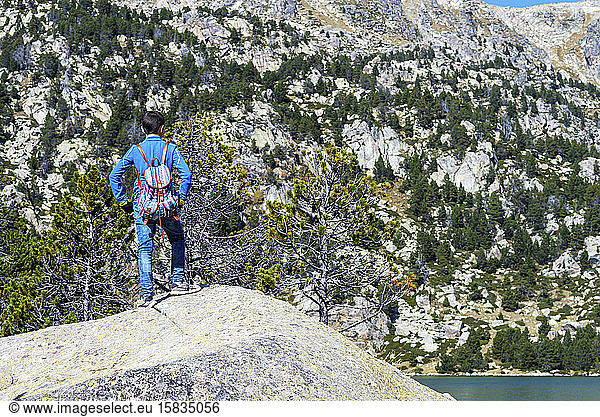 Rear view of a hiker boy standing against mountain at daytime