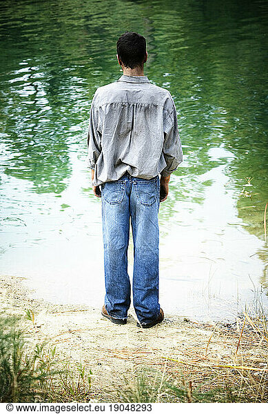 Rear view of a man standing at the waters edge.