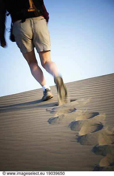 Rear view of a woman's legs walking up a sand dune in Death Valley National Park  California.
