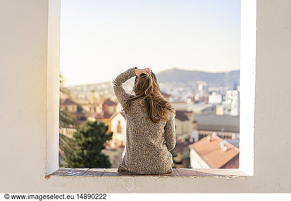 Rear view of a young woman sitting on a wall