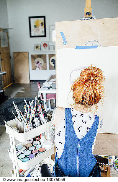 Rear view of artist drawing sketch on canvas in studio