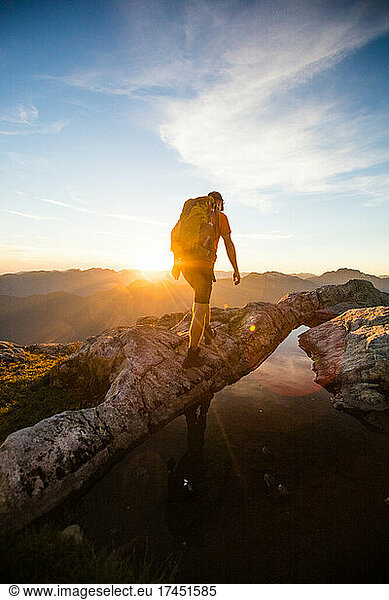 Rear view of backpacker hiking on mountain during sunset.