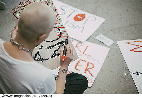 Rear view of bald female activist preparing signboard for social movement