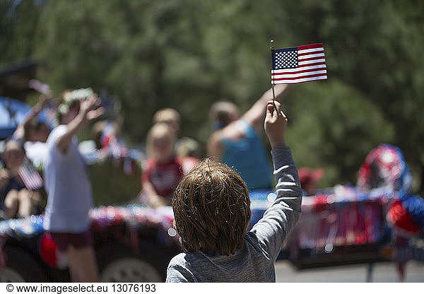 Rear view of boy holding American Flag during Independence Day celebration