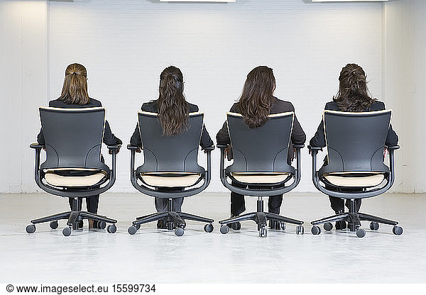 Rear view of business women sitting on office chairs.