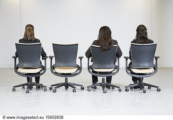 Rear view of business women sitting on office chairs.