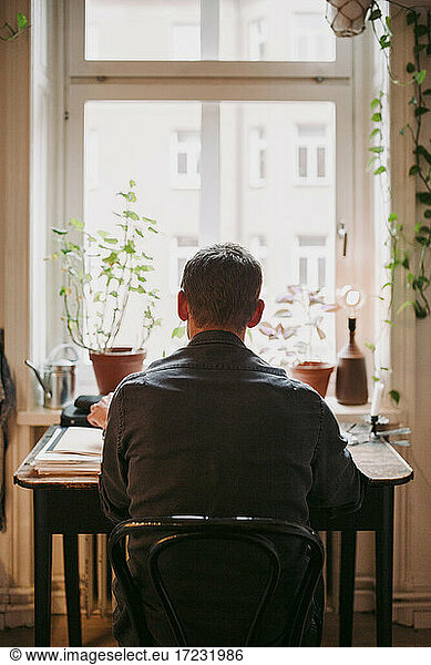 Rear view of businessman sitting on chair at home office