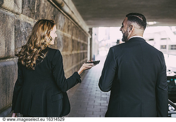 Rear view of businesswoman talking to businessman in city