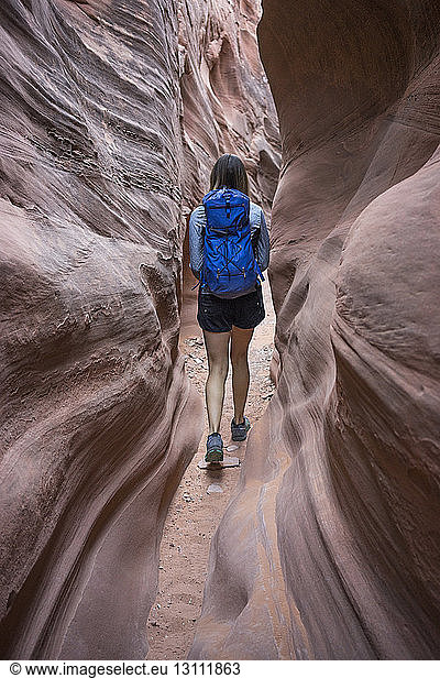 Rear view of carefree female hiker with backpack walking amidst canyons