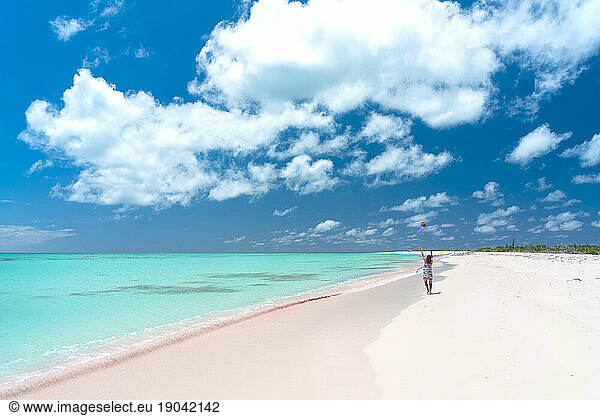 Rear view of cheerful woman on pink sand beach  Caribbean