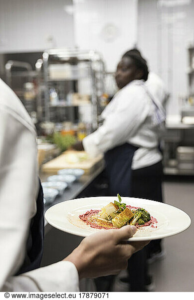 Rear view of chef carrying food in plate at restaurant kitchen