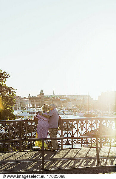 Rear view of couple looking at river while standing on bridge