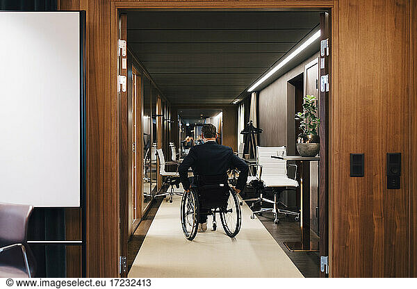 Rear view of disabled businessman on wheelchair in office