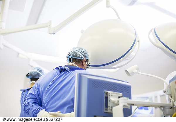 Rear view of doctor wearing surgical cap  mask and gown in operating theater