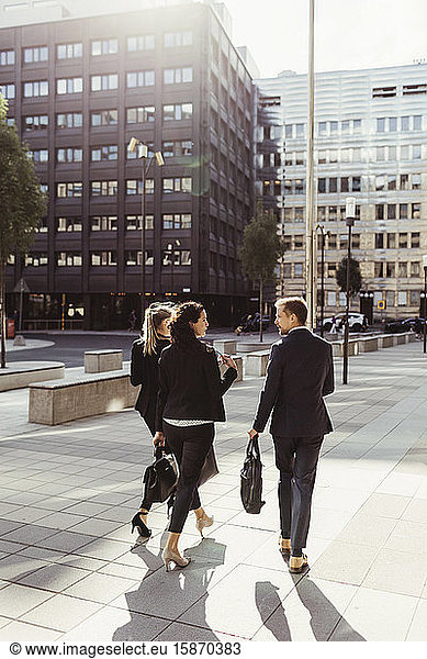 Rear view of entrepreneurs discussing business strategy while walking outdoors