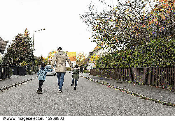 Rear view of father walking with children on footpath during autumn