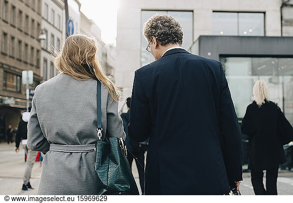 Rear view of female business person with male coworker in city
