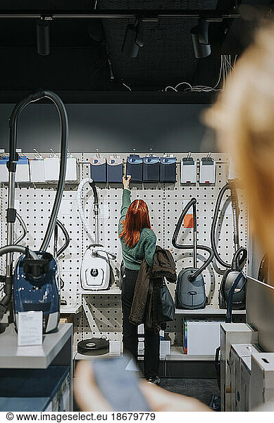 Rear view of female customer examining appliances while shopping in modern electronics store